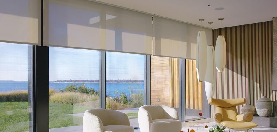 Lutron roller shades over a wall of windows facing the water